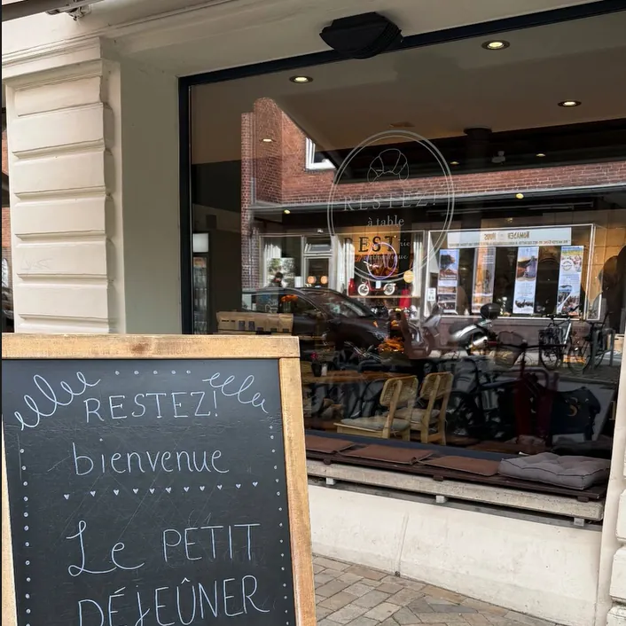 Kreidetafel „Restez! bienvenue – Le petit déjeuner“ vor dem Schaufenster in der Legienstraße