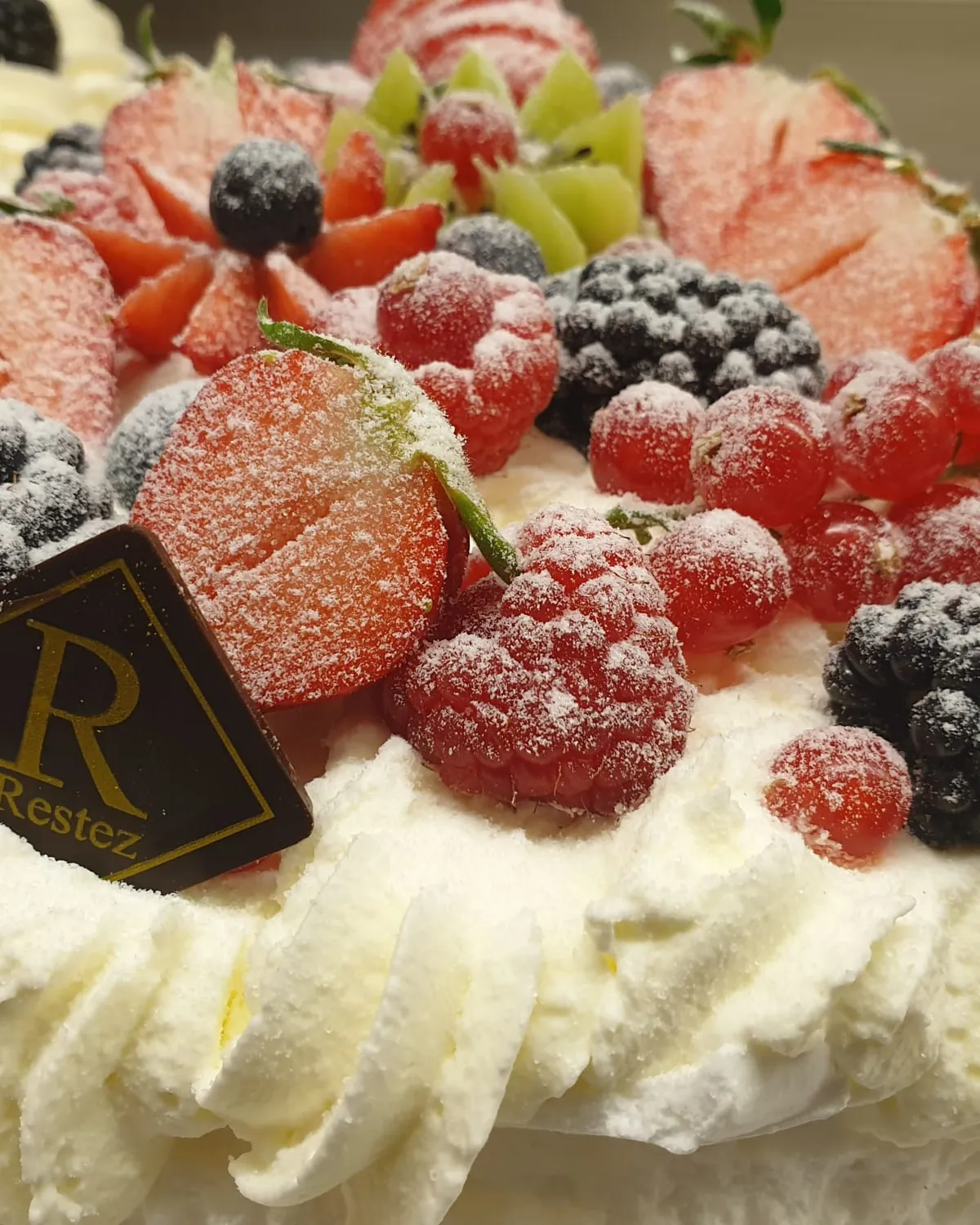 Sahnetorte mit gezuckerten Beeren und dem Restez-Zeichen